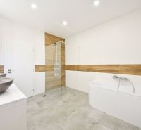 A bathroom in a family house with a bathtub, a shower, and a floor with a wooden decor.