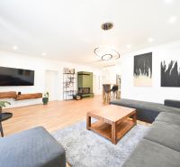 Living room in a family house with a large sofa, television, and wooden decor flooring.