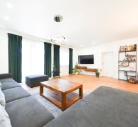 Living room with a large corner sofa and a wooden decor floor in a family house.