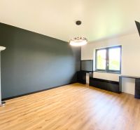In the family house, there is a spacious room with a black wall and a floor with a wooden decor.