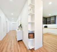 A kitchen in a family house with a wooden decor floor and white furniture.