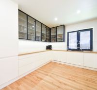 A kitchen in a family house with white cabinets and a wood-patterned floor.