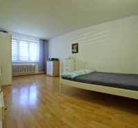 A bedroom with light, a bed, and a wooden decor floor in a two-room apartment.