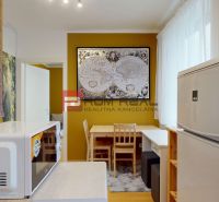 A kitchenette in a studio apartment, decorated with maps and wooden furniture.