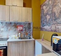 A kitchen in a studio apartment with a wooden decor and a map on the wall.