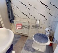 Bathroom in a studio apartment with a sink, toilet, and tiled wall.
