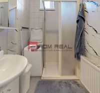 Bathroom in a studio apartment with a sink, washing machine, and shower stall with tiles.