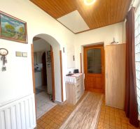 Chodba v rodinnom dome s podlahou s dreveným dekorom, obrazom a komodou.