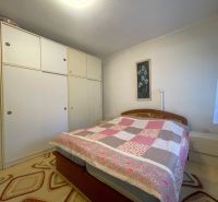 Spálňa v rodinnom dome s veľkou skriňou, kvetinovým obrazom a vzorovaným kobercom.