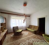 A living room in a cottage with older furniture and lighting, carpeted floor.