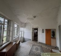 The interior of the cottage with carpet and tiles, wooden furniture, and large windows.