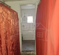 A narrow hallway with curtains leading to the bathroom in the cottage.
