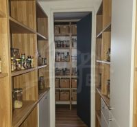 The cottage has a pantry with shelves featuring a wooden decor and storage baskets.