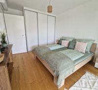 A bedroom with wood-patterned flooring in a 3-room apartment, decorated with green accessories.