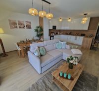 Living room of a 3-room apartment with a wooden decor floor, dining table, and sofa.
