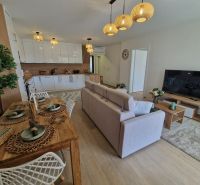 3-bedroom apartment with a kitchen, dining table, and wooden decor flooring.