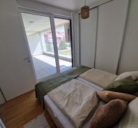 Bedroom in a 3-room apartment with wood-patterned flooring and access to the terrace.