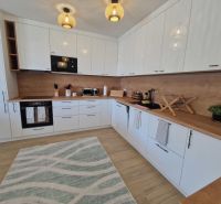 A modern kitchen in a 3-room apartment with light furniture and a wooden decor floor.