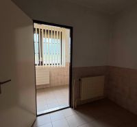 Interior commercial spaces with tiles and a radiator, light passes through vertical blinds.