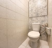 Toilet in the bathroom of a 3-room apartment with white tiles and ceramic flooring.