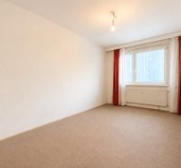 A room with carpet flooring and a window in a 3-room apartment, simple curtains.