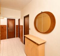 A hallway in a 3-room apartment with a round mirror and a wooden decor floor.