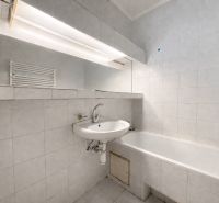 Bathroom in a 3-room apartment with a bathtub and a sink, white tiles.