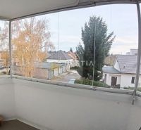 Enclosed balcony of a 3-room apartment in Senica with a view of gardens and rooftops.