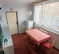 Dining nook with a window, patterned wallpaper, wood-patterned flooring, and a checkered tablecloth.