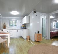 Interior of a family house with a wooden decor floor, kitchen, and dining table.