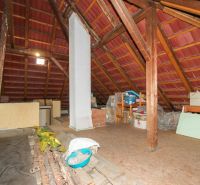 Attic room in a family house with wooden beams and stored items.