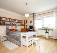 A room in a family house with a bed, a bookshelf, and a table, with a wooden decor floor.
