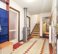 A hallway in a family house with tiles, a staircase, and colorful flooring.