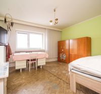 A room in a family house with a green wall, a bed, and a wardrobe, with a wooden decor floor.