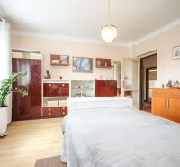 A family house with a wooden decor floor, wardrobes, a bed, and a potted plant.