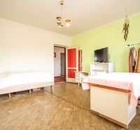 A room with a wooden floor decor, a table, a bed, and a television in a family house.