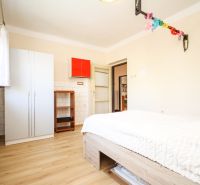 A room with a bed, a wardrobe, and a wooden floor decor in a family house.