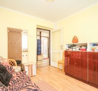 A room with wooden floor decor, a sofa, and storage cabinets in a family house.