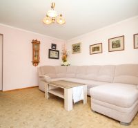 Living room in a family house with a beige sofa, coffee table, and wall paintings.