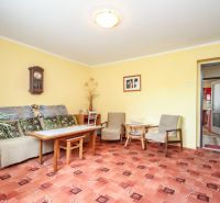 Living room in a family house with carpet flooring, furniture, and a wall clock.