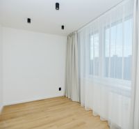 A room in a 4-room apartment with light-colored walls, a window, and a floor with a wood decor.