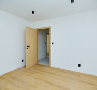 An empty room with wood-patterned flooring and open doors in a 4-room apartment.