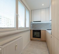 The kitchen of a 4-room apartment with a kitchen unit and large windows with blinds.
