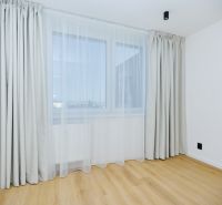 A room in a 4-room apartment with a wooden decor floor, curtains, and drapes.