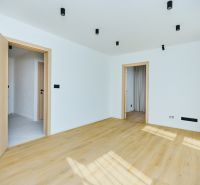 A room with a wooden decor floor and white walls in a 4-room apartment.