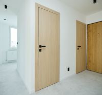 Interior of a 4-room apartment with a wooden decor floor and light doors.