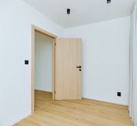 Interior of a 4-room apartment with white walls and a floor with a wood decor.