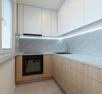 A kitchen in a 4-room apartment with a wood-patterned floor and sleek design.