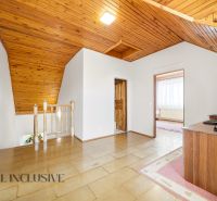 Attic space in a family house with wooden ceiling paneling and flooring with a wooden decor.