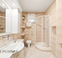 A bathroom in a family house with a sink, shower, and toilet on beige tiles.